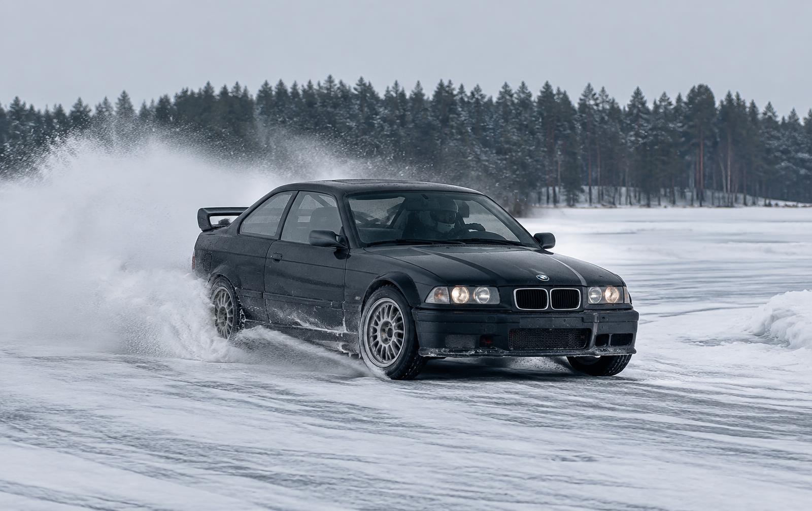 Dark coupe drifting across a snow-covered lake track