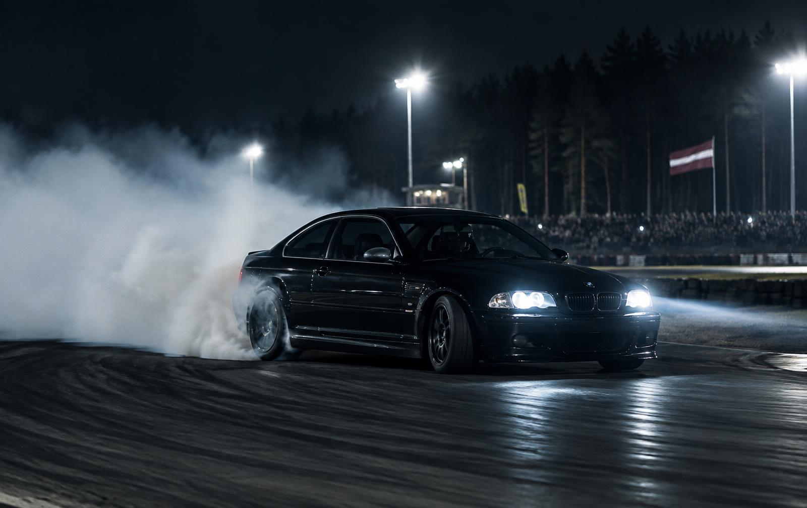 Rear-wheel-drive coupe drifting under track lights